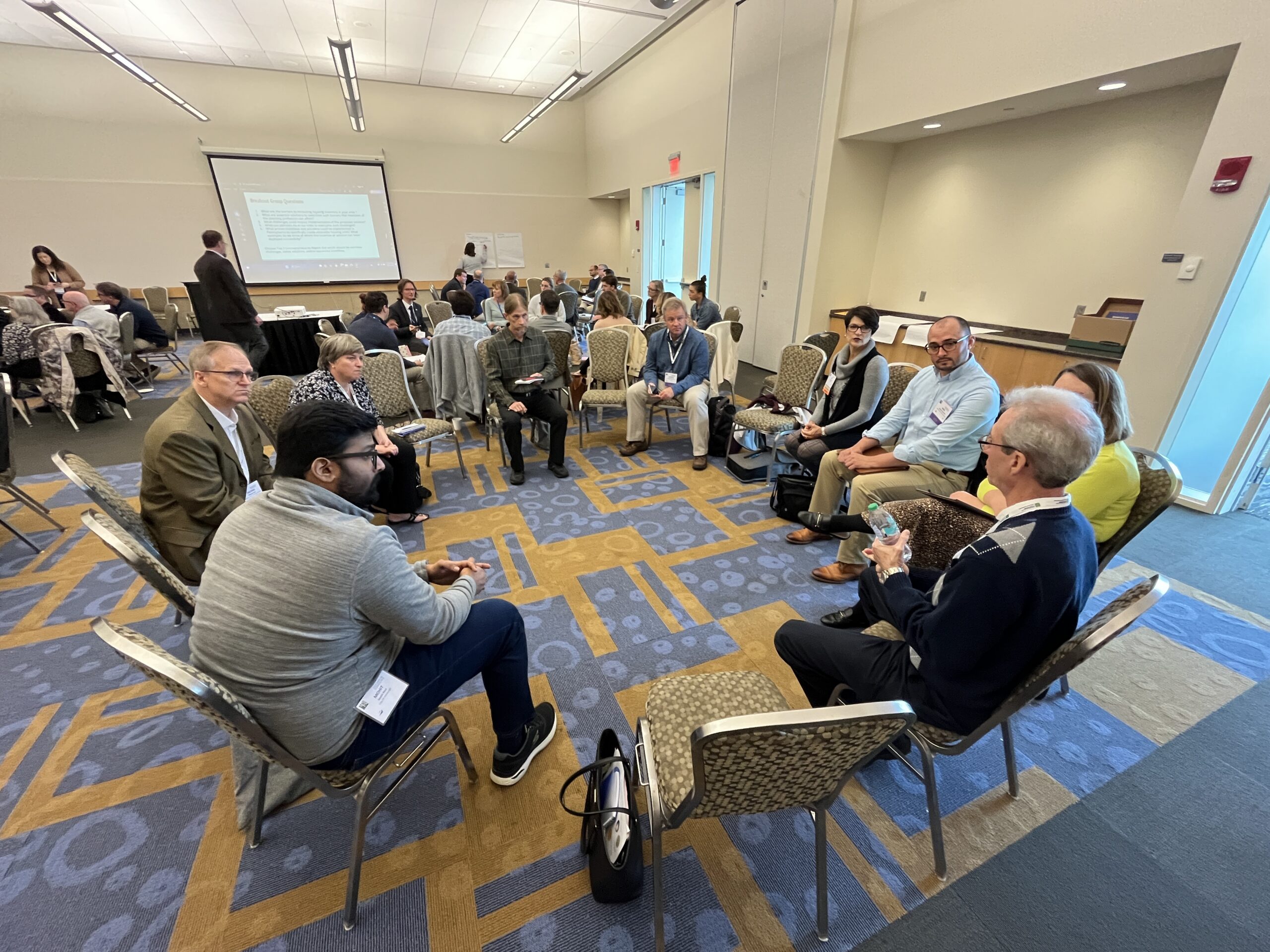 A group of conference attendees sits in a circle for a small group discussion