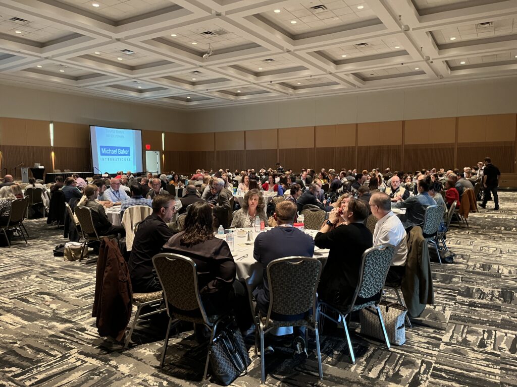A plenary session in a large ballroom with planners sitting at round tables