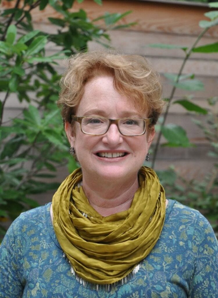 Woman with glasses and an olive-colored scarf around her neck