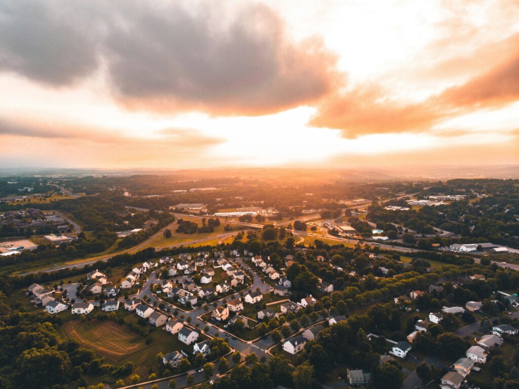 Aerial image showing houses in a subdivision in the foreground with the sun setting in the background
