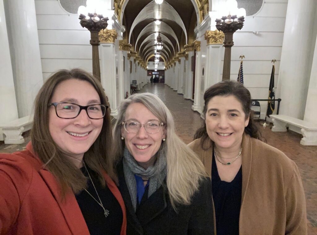 Three women stand in the hallway of a government building